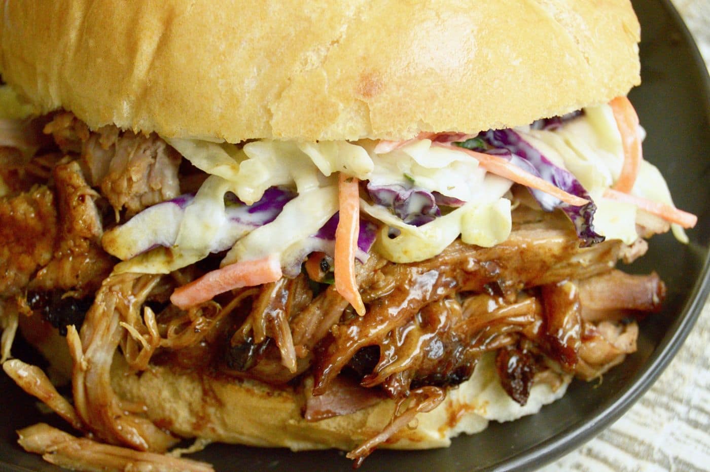 close up of pulled pork sandwich with bbq sauce on top