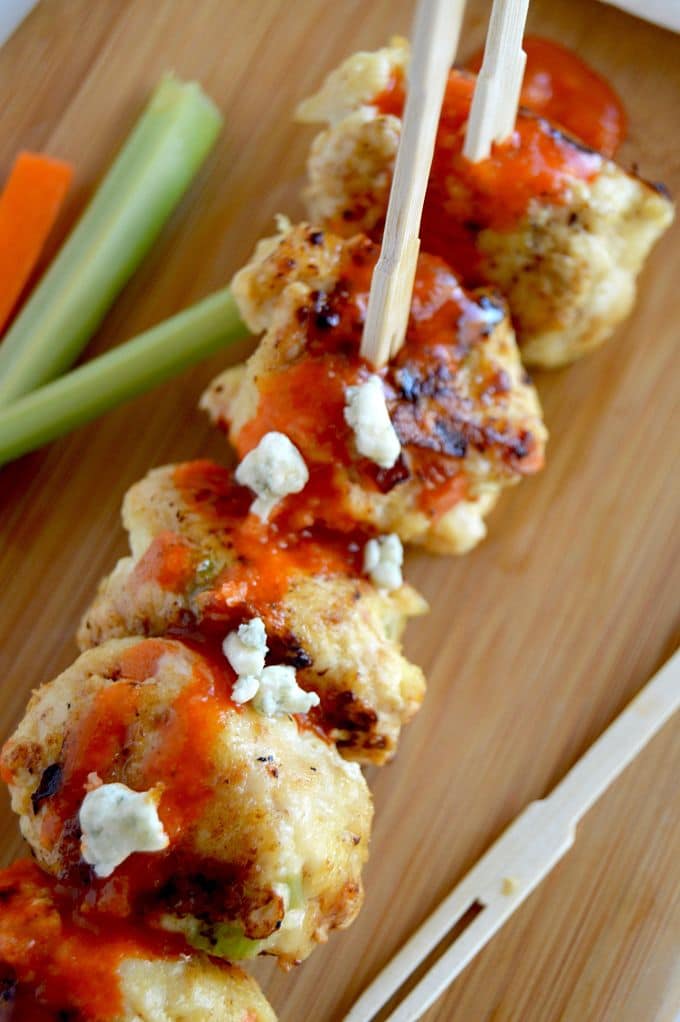 Buffalo Chicken meatballs on a platter with sauce and blue cheese drizzled over the top