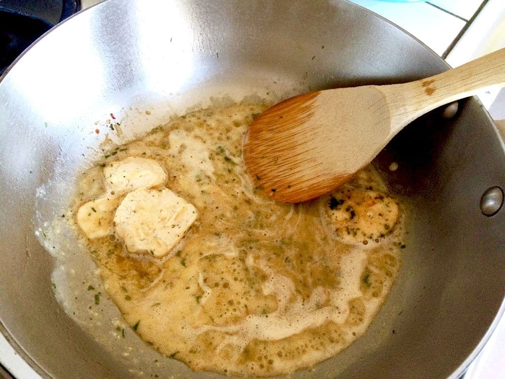 Compound Butter for Cajun Shrimp/ Spicy BBQ Shrimp, Ruths Cris Appetizer shown melting in a sauce pan being stirred with a wooden spoon