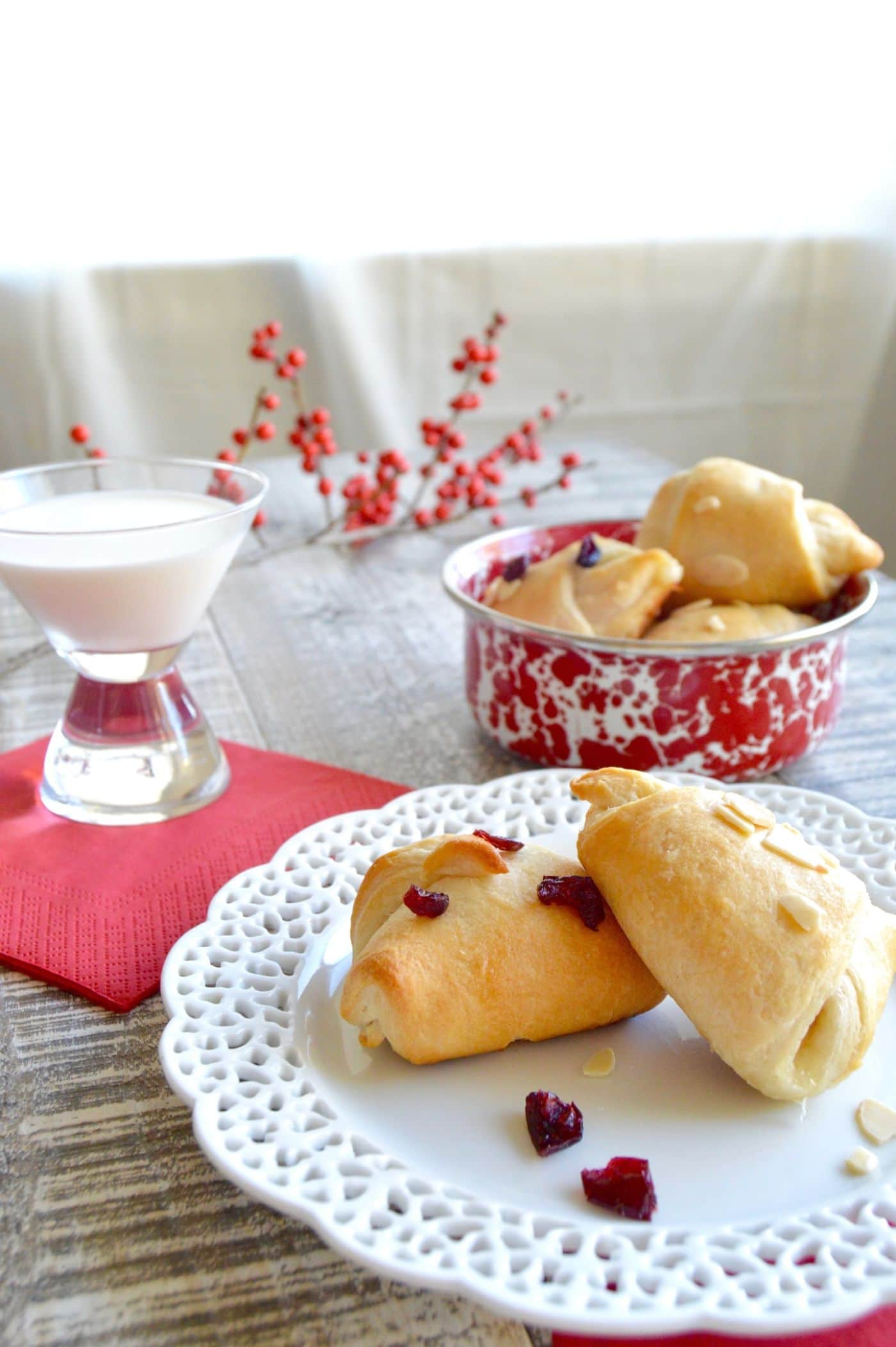 Party Brie Cheese Crescent Bites a white plate with a glass of milk next to them in a holiday table setting with red holly berries!