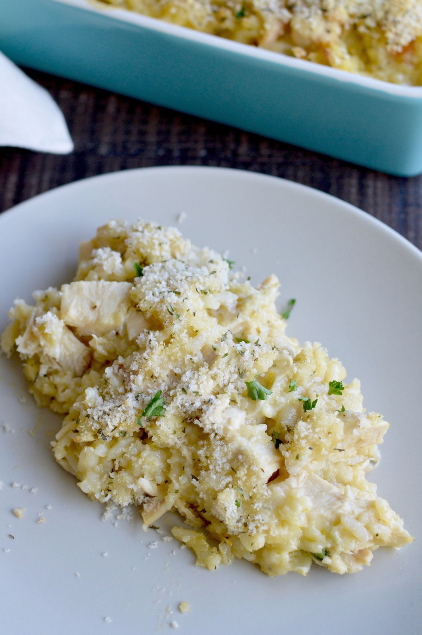 Artichoke Casserole with chicken scooped out onto a white plate on a brown table