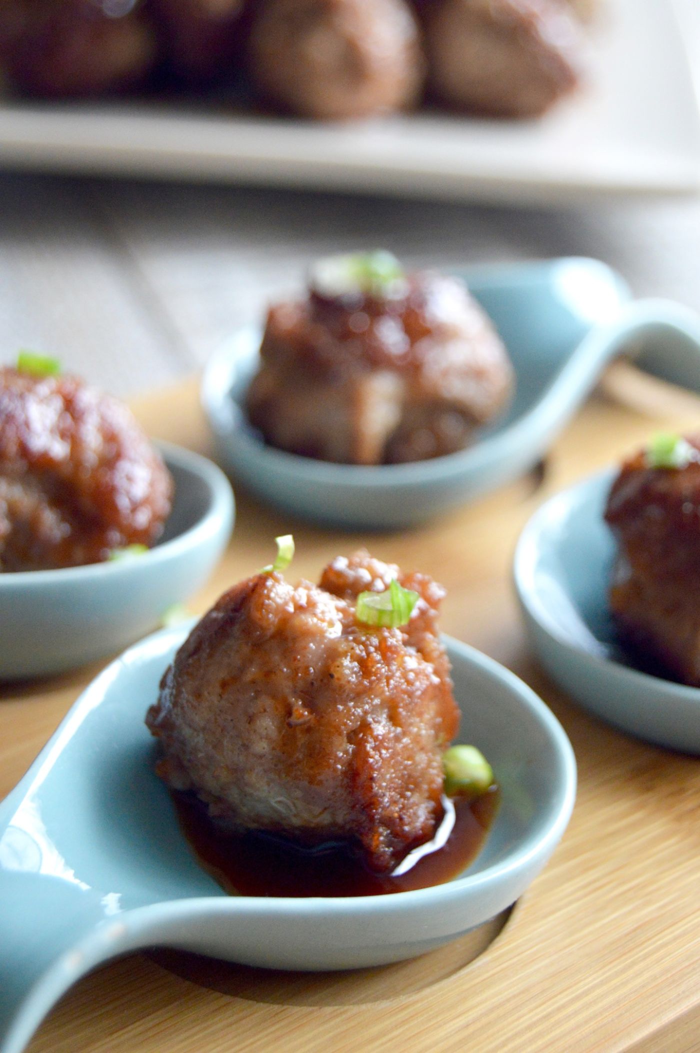 Chinese Pork meatballs: in individual Blue Chinese serving spoons with a closeup with sauce drizzled over the top.