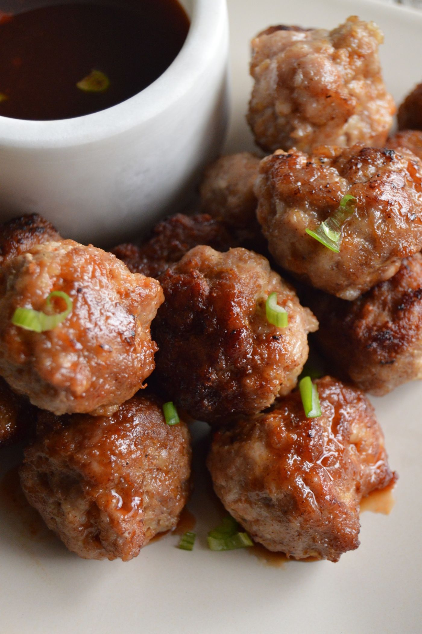 Easy way to serve meatballs. Chinese Pork meatballs: Stacked on a tan plate, with sauce in a white bowl next to it