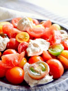 plate of tomato salad with fresh burrata on top