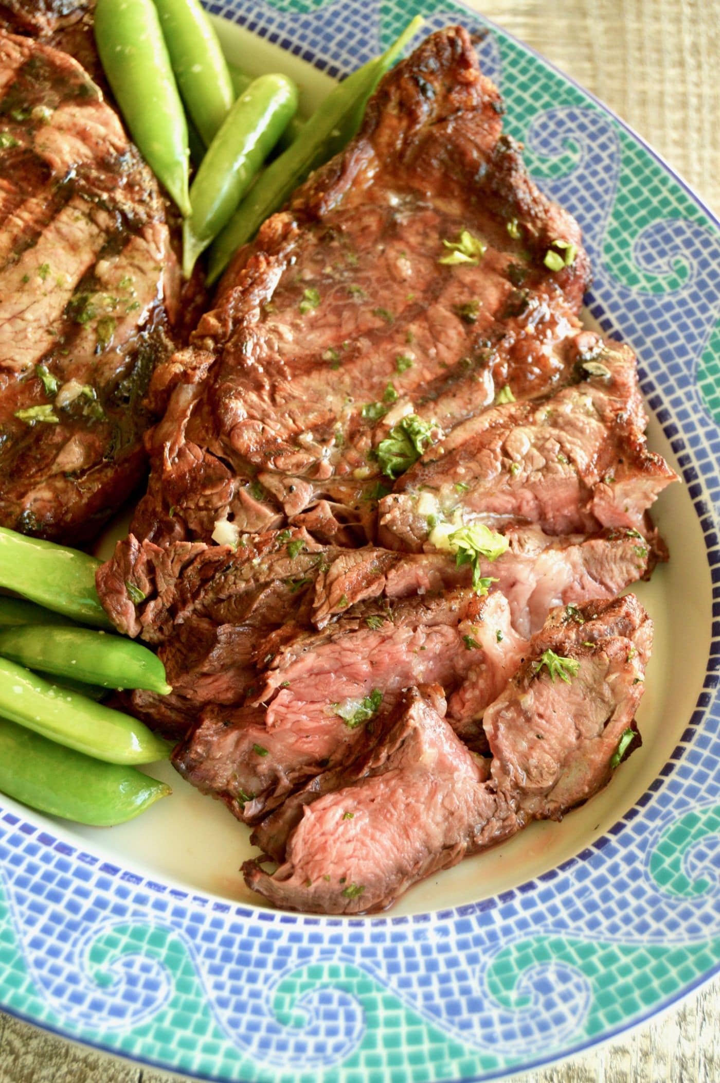 Sliced grilled ribeye with melted bourbon butter on a mosaic plate