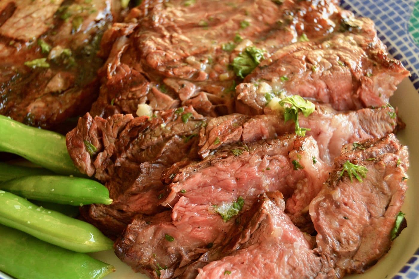 rare ribeye steak with grill marks sliced on a dinner plate with snap peas