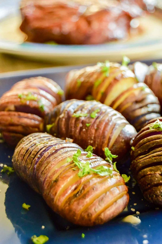 sliced hasselback potatoes with parsley on a blue plate