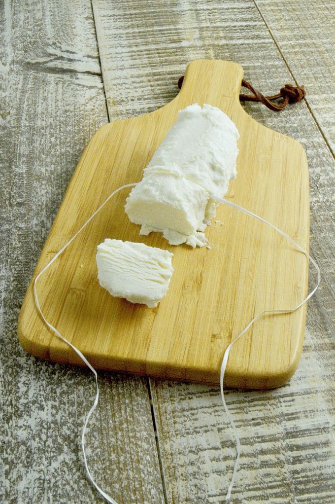 Warm goat Cheese salad| cutting the goat cheese into rounds with dental floss on a cutting board