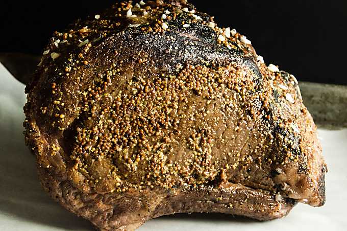 Process shot showing the Horseradish Crust Ribeye Roast seared and coated with mustard before going into the oven