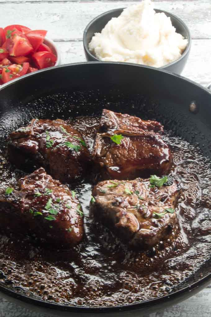 Pan Seared loin lamb chop recipe in the pan with the bubbling balsamic glaze all around them.