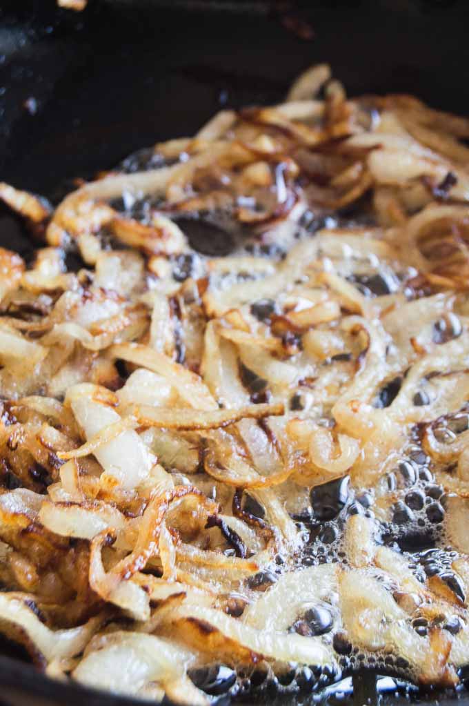 Slow Sauteed Onions in a pan sizzling to top Roast Beef Sliders