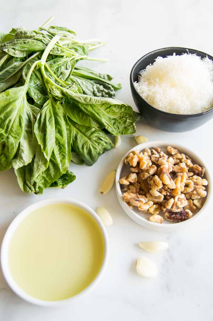 All of the ingredients to make pesto basil, walnuts, warm, oil and garlic