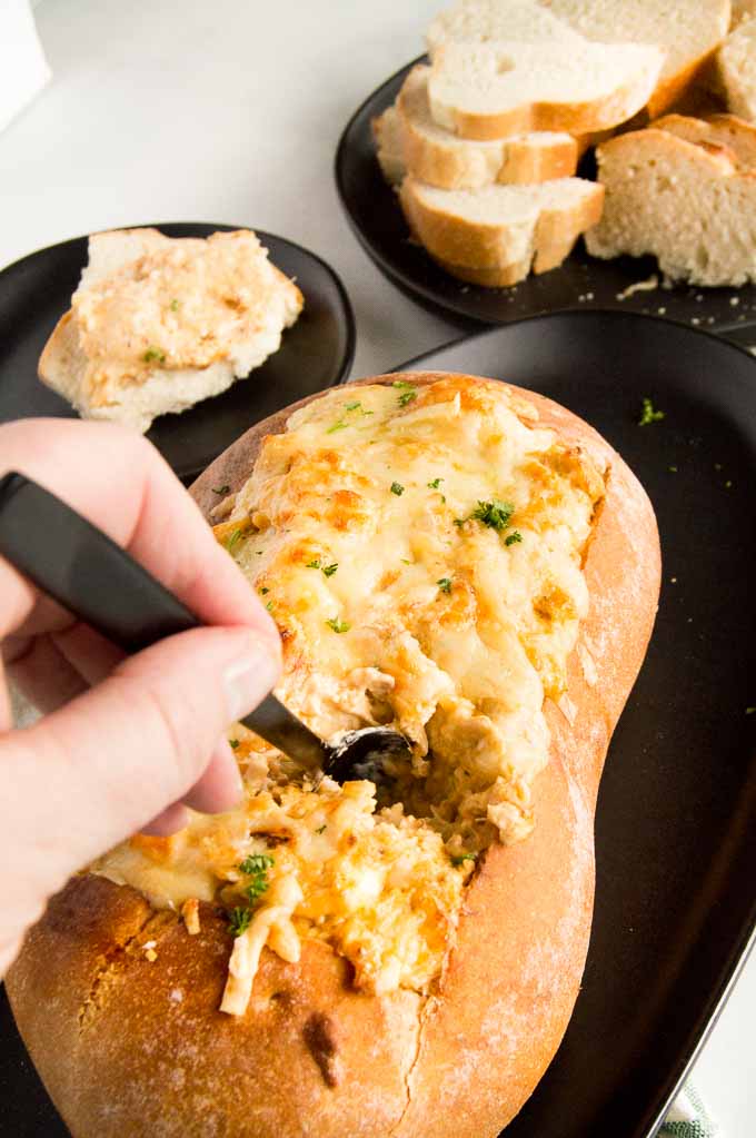 Spreading Hot crab dip from a bread bowl
