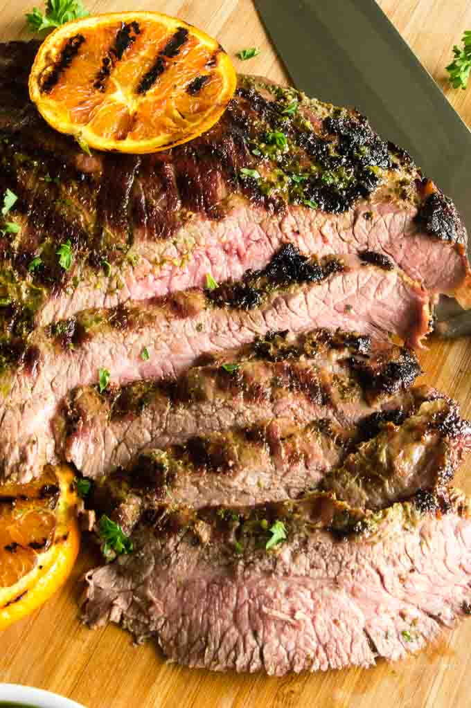 1/4" slices of flank steak cut across the grain on a cutting board.