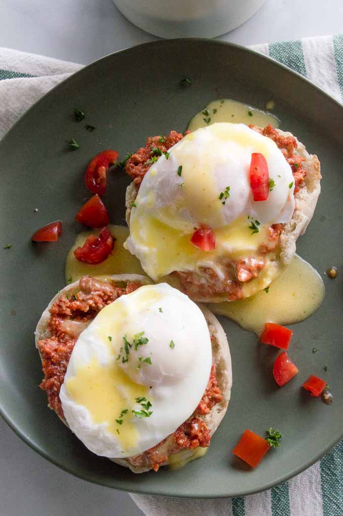 Italian Eggs Benedict served with tomatoes on a plate