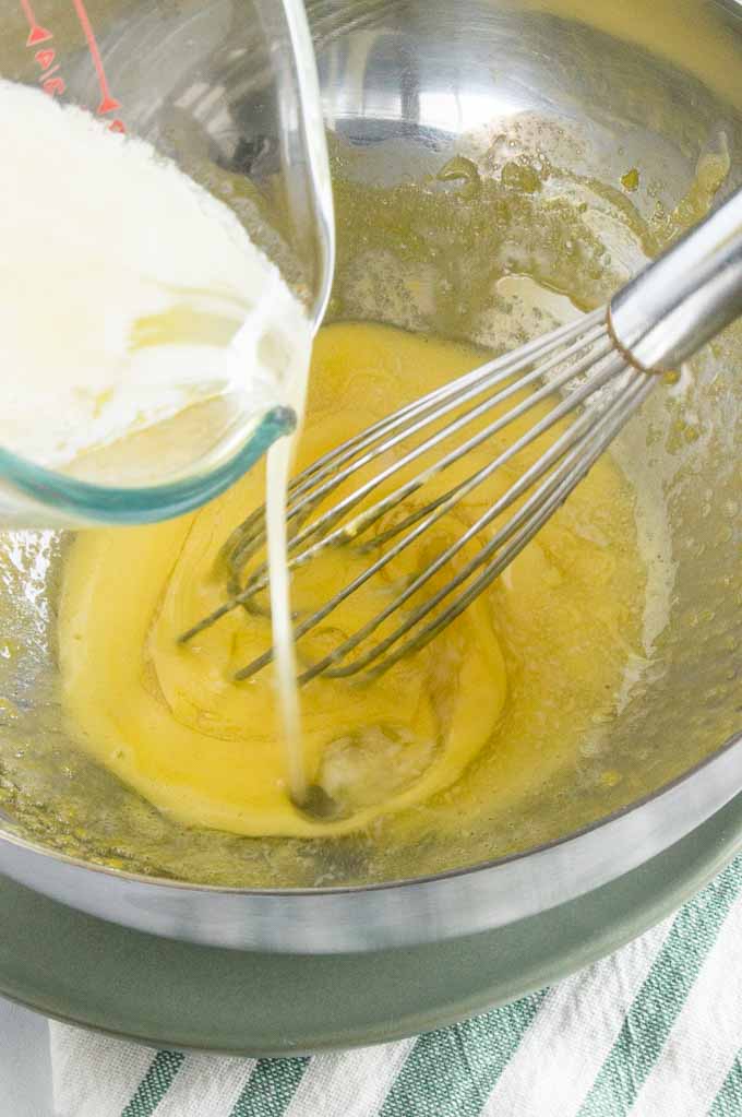 slow drizzle butter being added to egg yolks