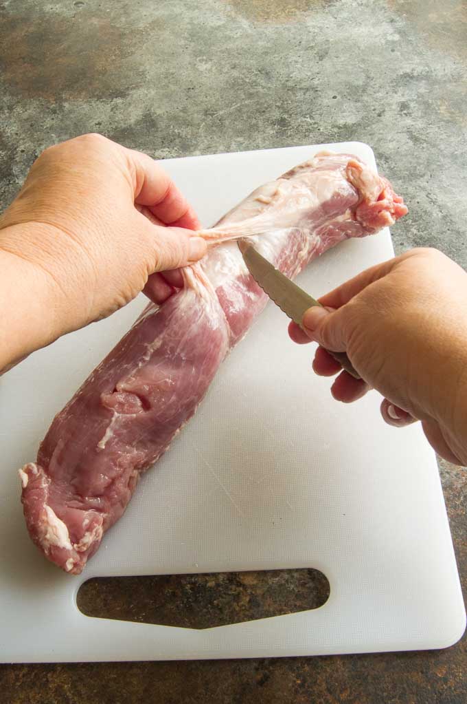 Inserting the knife to remove the membrane from the pork tenderloin