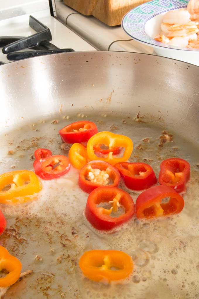 Sauting peppers in melted butter for shrimp Alfredo recipe