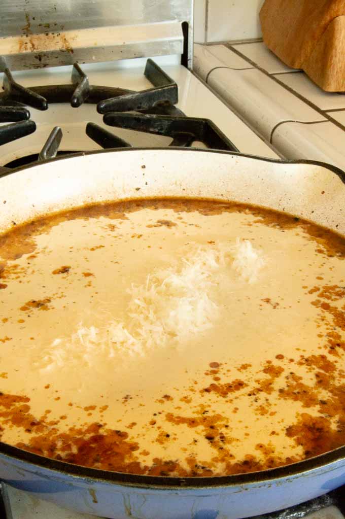 Adding parmesan and milk to the creamy garlic sauce for tuscan chicken