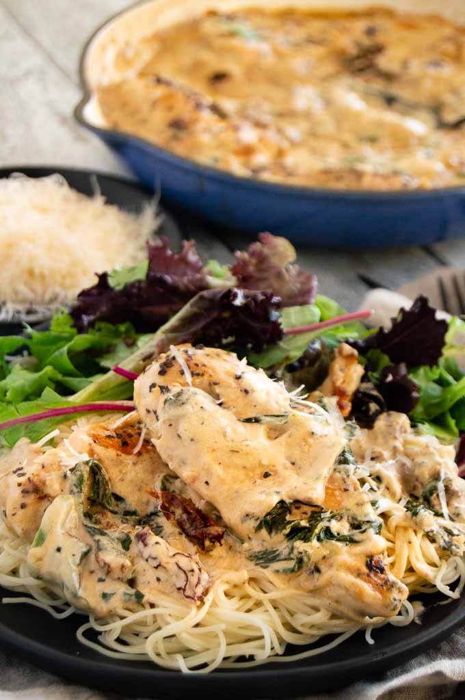 Creamy tuscan garlic chicken on the plate with a salad