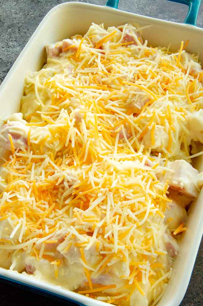 ham and potato casserole topped with cheese ready to go into the oven