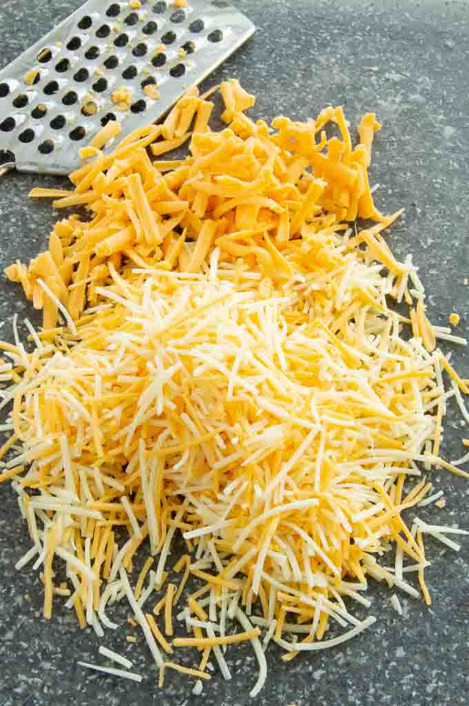grated cheeses on a cutting board to go on the hot dish