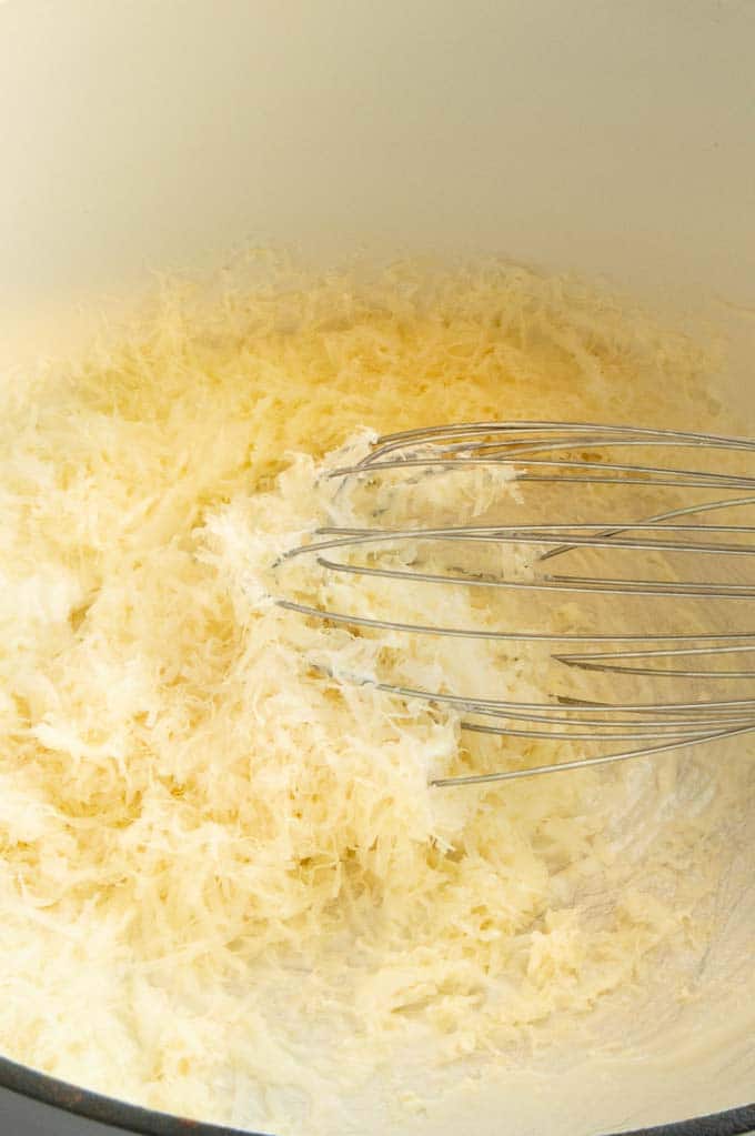 parmesan cheese being stirred into creamy cajun pasta