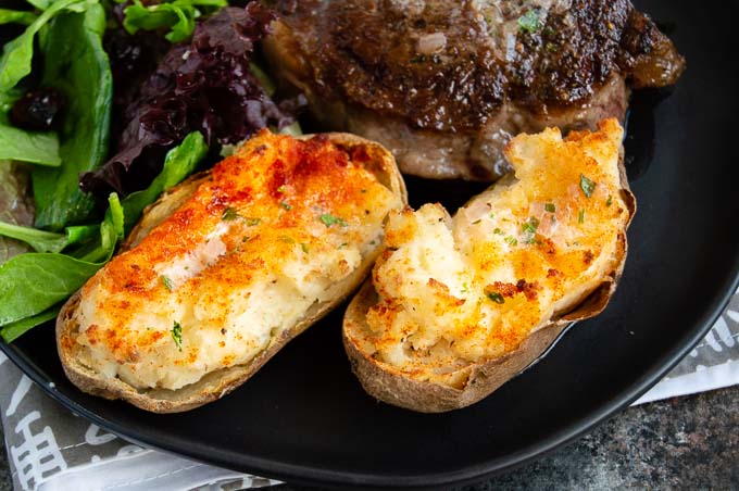 Twice baked potatoes are a fancy side dish that pair beautifully with any meal.  Crunchy tops with creamy, tangy potatoes underneath make this double baked potato a popular choice for special occasion steak dinners at home!