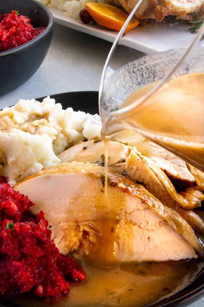 Pouring homemade gravy over sliced turkey