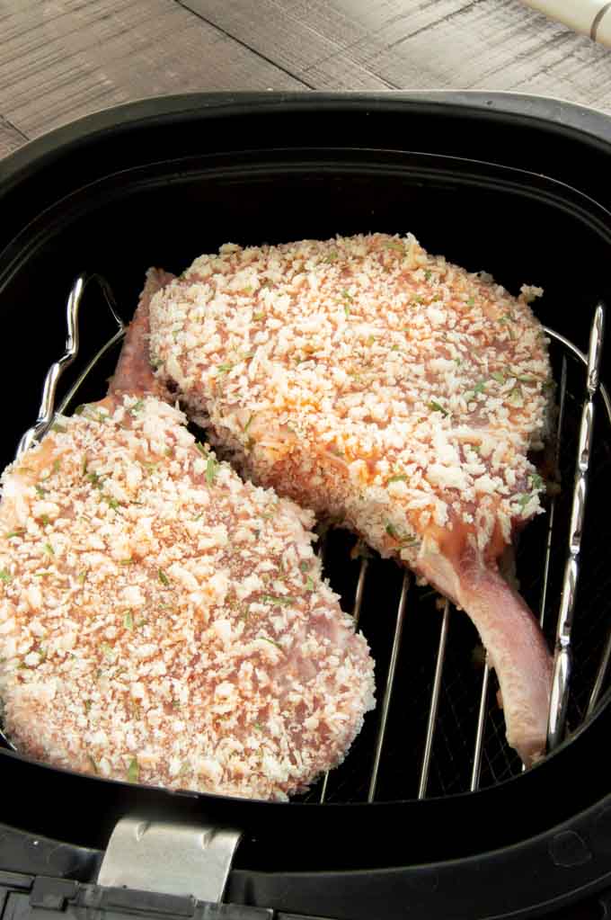 Coated pork chops placed in the air fryer basket