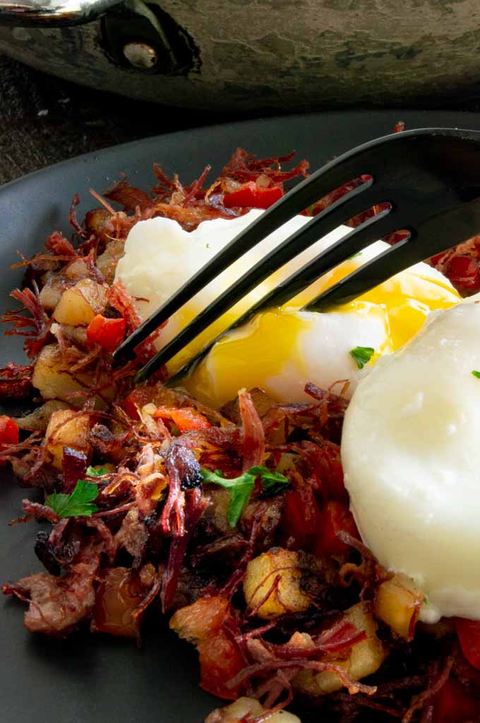 Creamy egg yolk dripping over the top of the corned beef hash