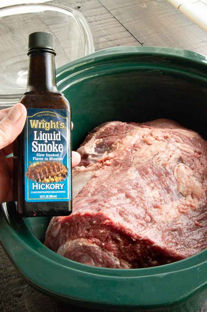 showing the liquid smoke bottle that is used to season the brisket below