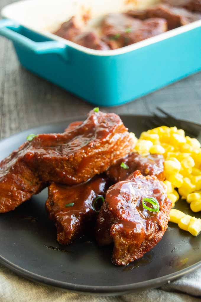 boneless pork ribs on a black plate with corn