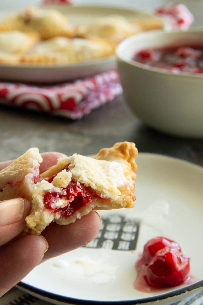 a just bitten into cherry hand pie with a flaky crust