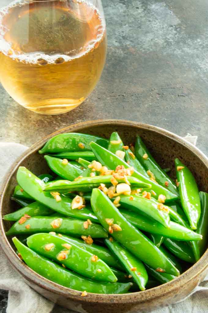 Serving bowl with fresh sugar snap peas and garlic