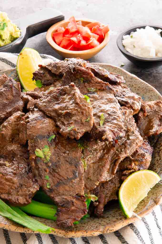 plate of Carne Asada with tomatoes, onions and cilantro on the side