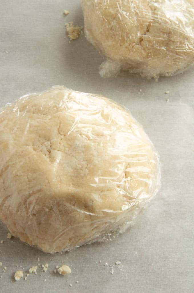 Pie crust discs wrapped in plastic to go in fridge for chilling