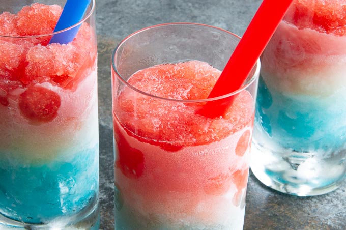 3 glasses with red white and blue cocktails in them