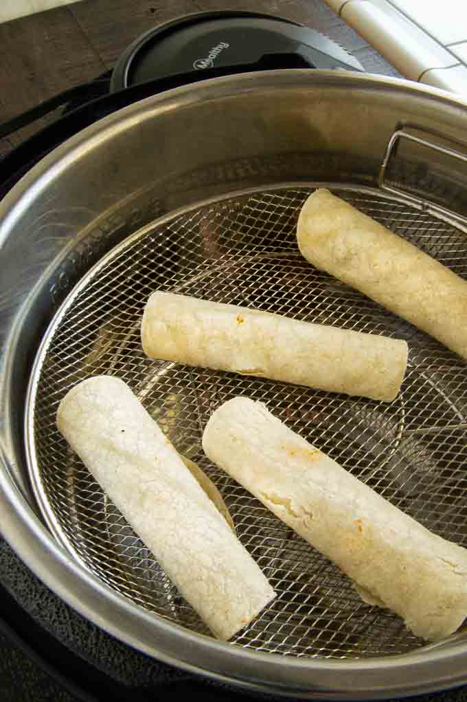 taquitos in the air fryer before cooking. showing space between them (1")