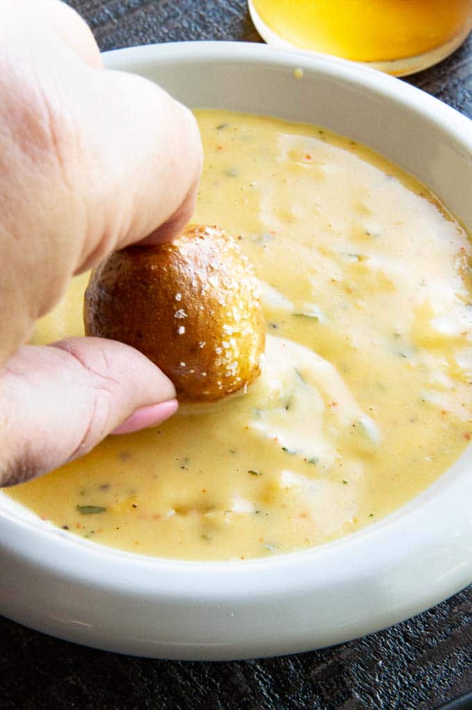 dipping a soft pretzel into beer cheese dip