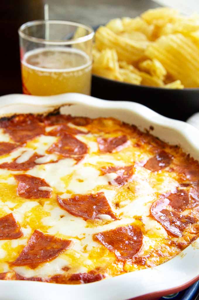 buffet table with pan of layered pizza dip and chips on it