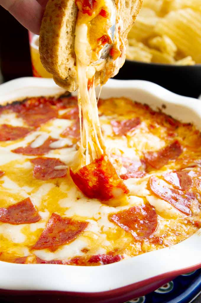 hot pizza dip with melted cheese being pulled while serving
