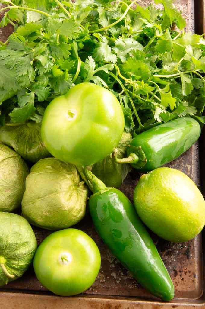 tomatillos, cilantro, onions and limes on a tray for green salsa