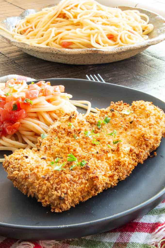 Dinner table with schnitzel and pasta on a black plate