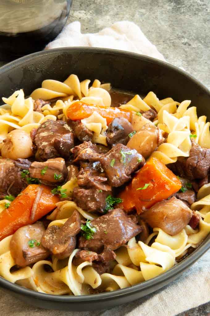 Bowl of beef stew over noodles with gravy
