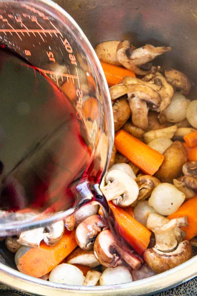 pouring wine into instant pot over veggies