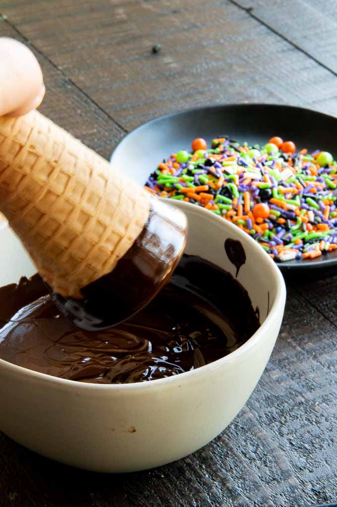 dipping the ice cream cones in melted chocolate