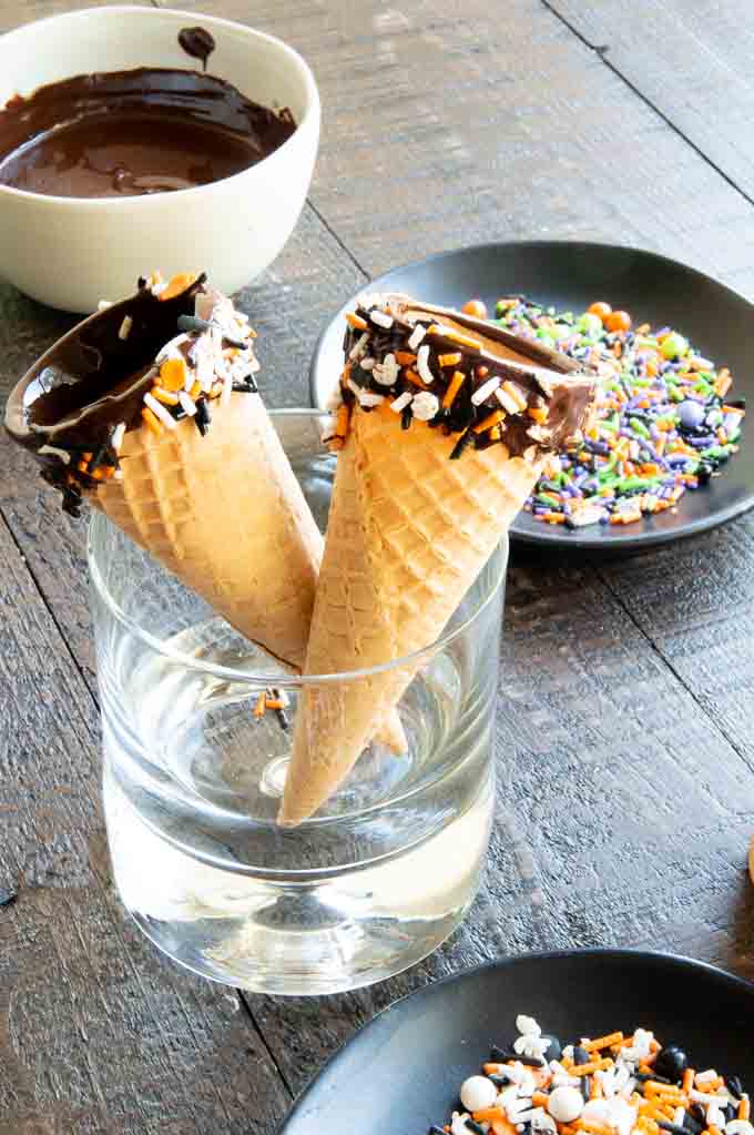 Chocolate Dipped cones with sprinkles setting to harden in a short glass