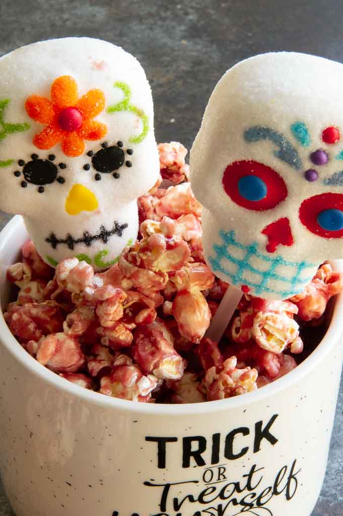 sugar skull marshmallows in a container of caramel popcorn.