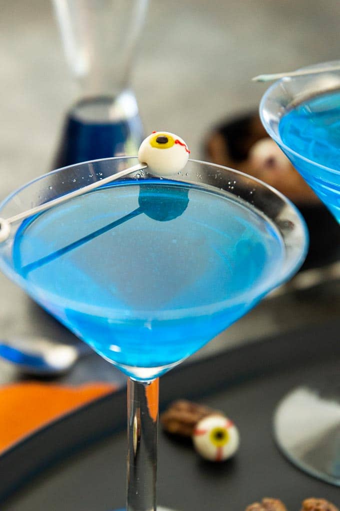 Bright Blue Ghouls Blood Cocktail in martini galss with an eyeball "olive"